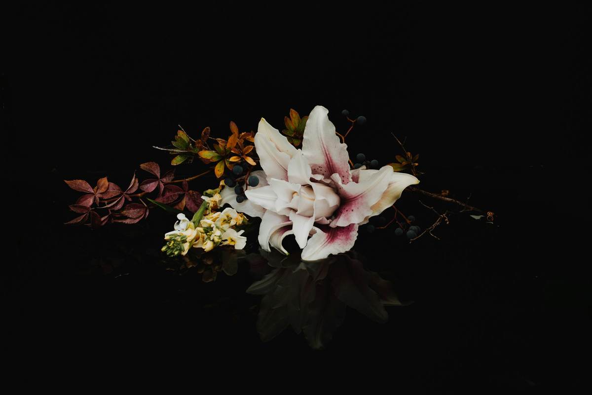 Bloemstuk met witte lelies en donker blad