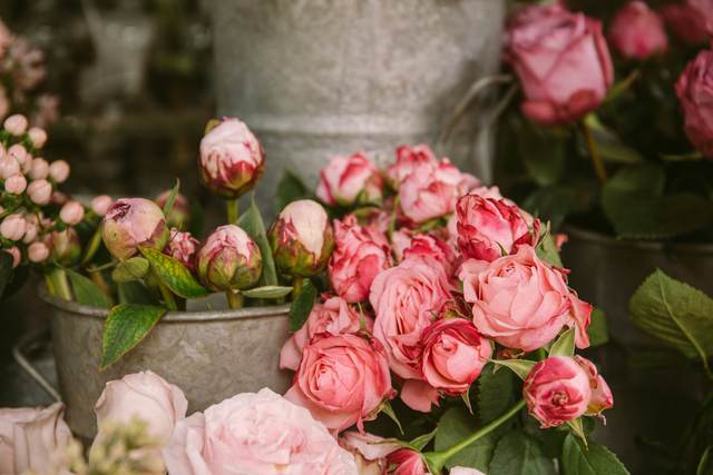 Roze rozen en pioenknoppen in een metalen emmer