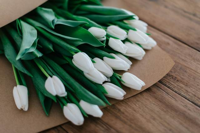 Witte tulpen in papier op een houten tafel