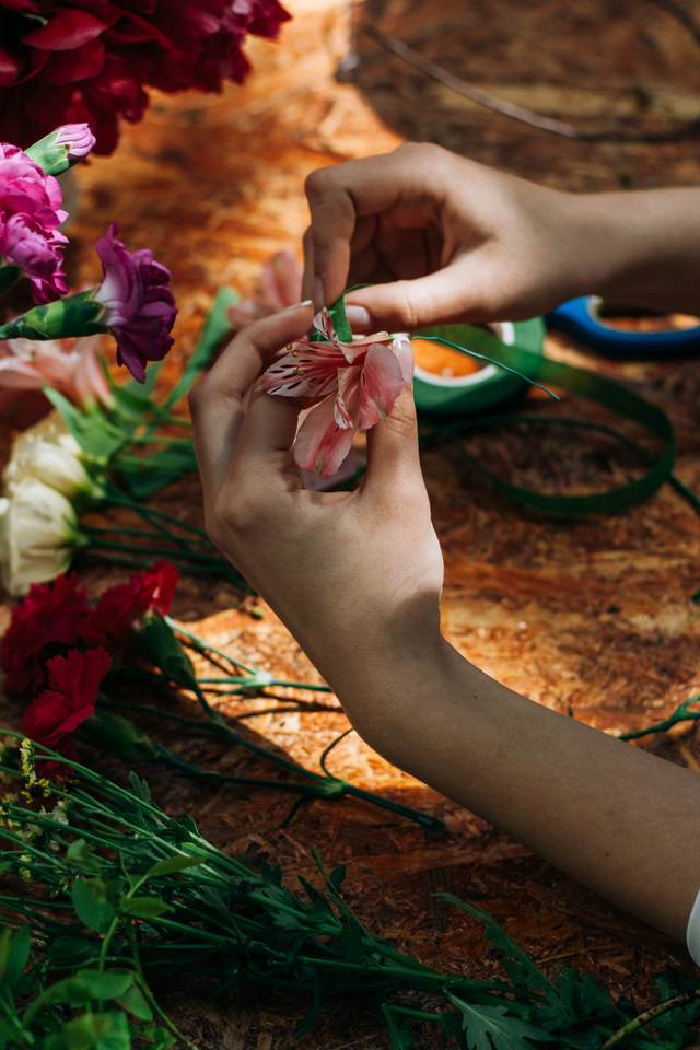 Handen die bloemen schikken aan een werktafel